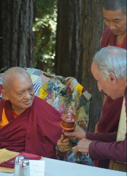 Chuck offering a handheld prayer wheel to Lama Zopa Rinpoche at Vajrapani Institute